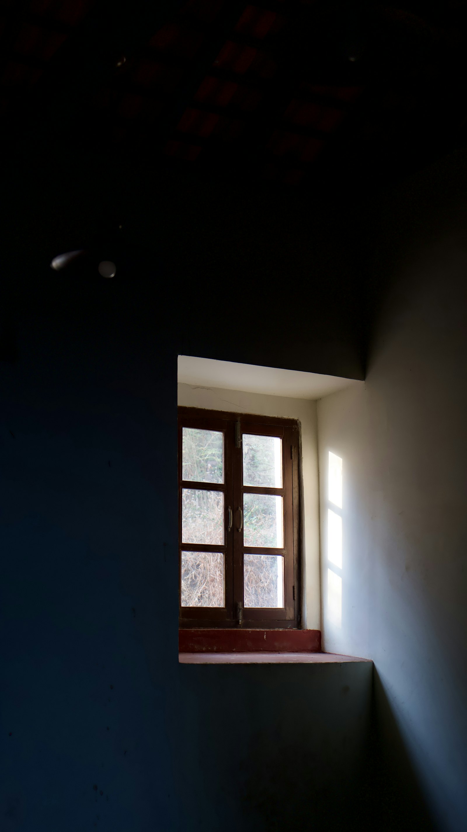 Tageslicht fällt durch ein Fenster in einen dunklen Raum.